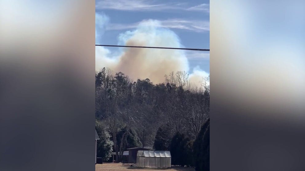 A wildfire can be seen burning in the mountains behind a home in Old Fort, North Carolina, where many homes were devastated by Helene in late September. 