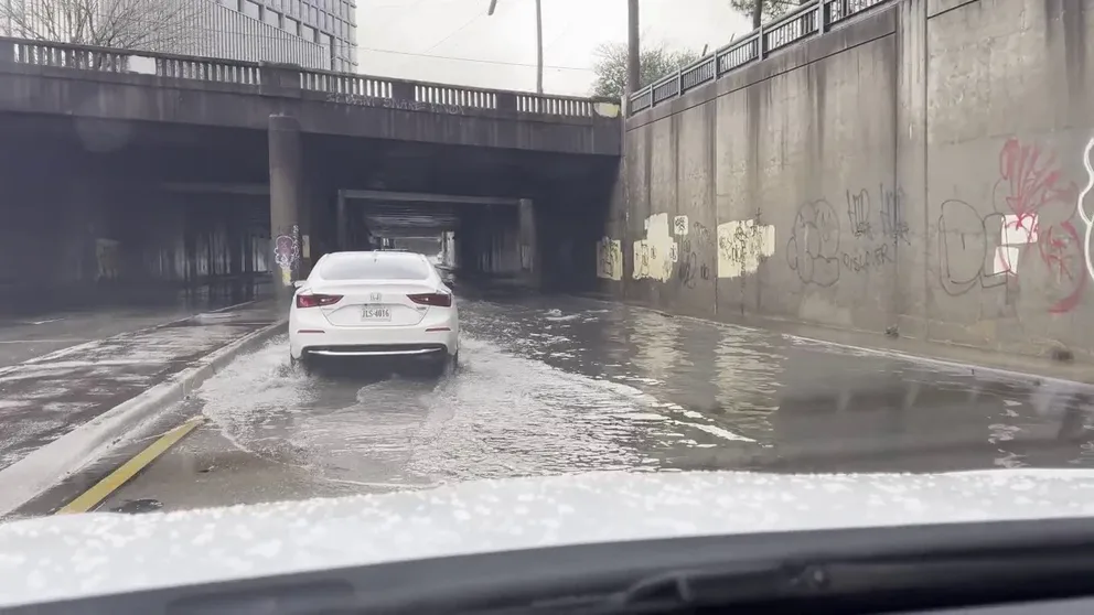 Rain brought on by severe storms hitting the southeast left some flooded roads in Atlanta Sunday morning. Video shows cars driving through a flooded road in midtown Atlanta. 