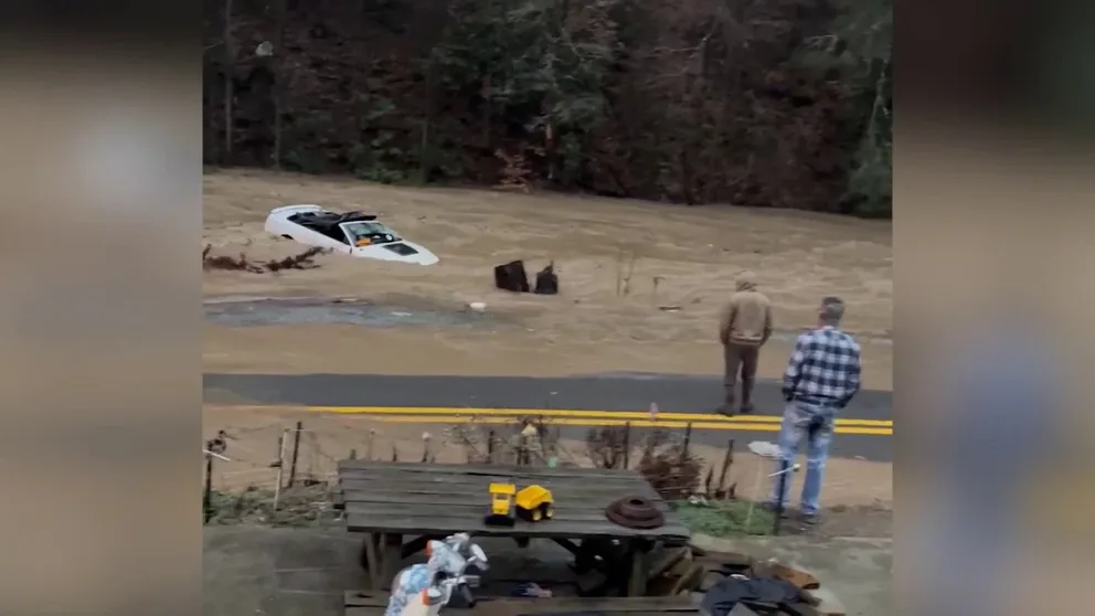 Video shot on Saturday shows a white Ford Mustang convertible being swept downstream by powerful floodwater in Panther, West Virginia.