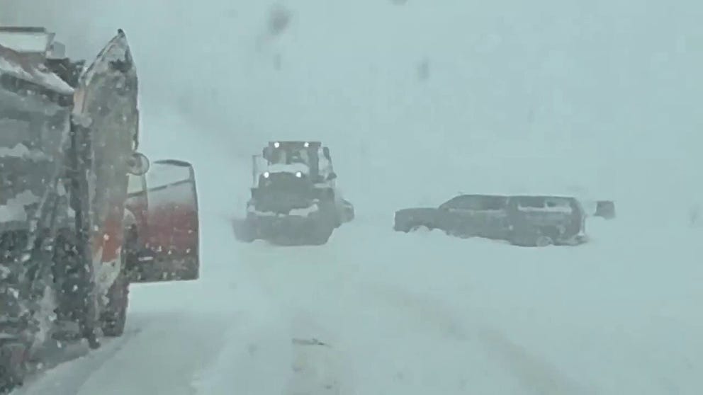 Crews work to dig out two vehicles partially buried in the heavy snow.