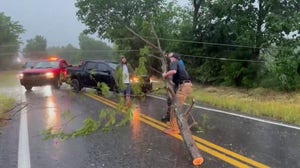 People in Pittsburg, Oklahoma, stop on the road to remove a downed branch on a powerline