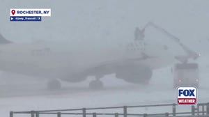 Crews work to de-ice a plane at an airport in Rochester, New York, on Tuesday