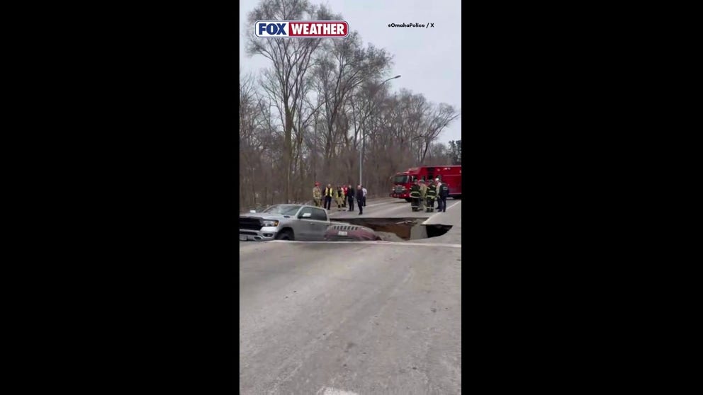 Officers from the Omaha Police Department respond to a sinkhole in the middle of a busy street.