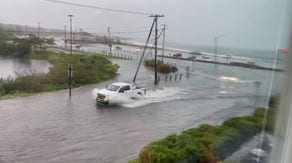 Cars travel through flooded roadways near Rhode Island beach