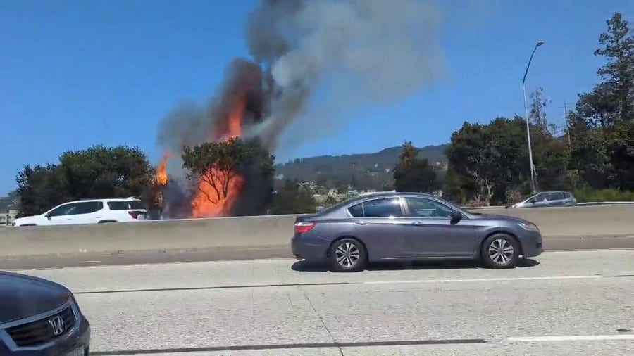 Drivers watch as a large fire burns along Oakland highway