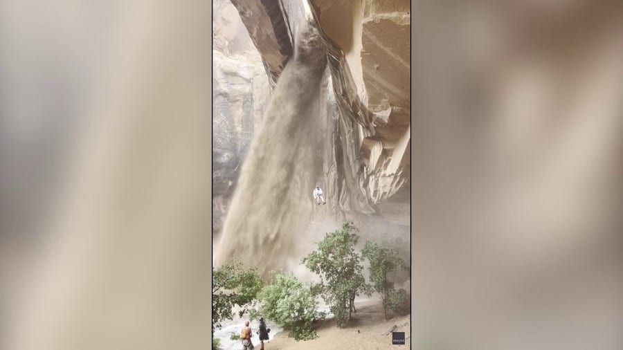 Climber rappels next to raging waterfall that developed during flash flood