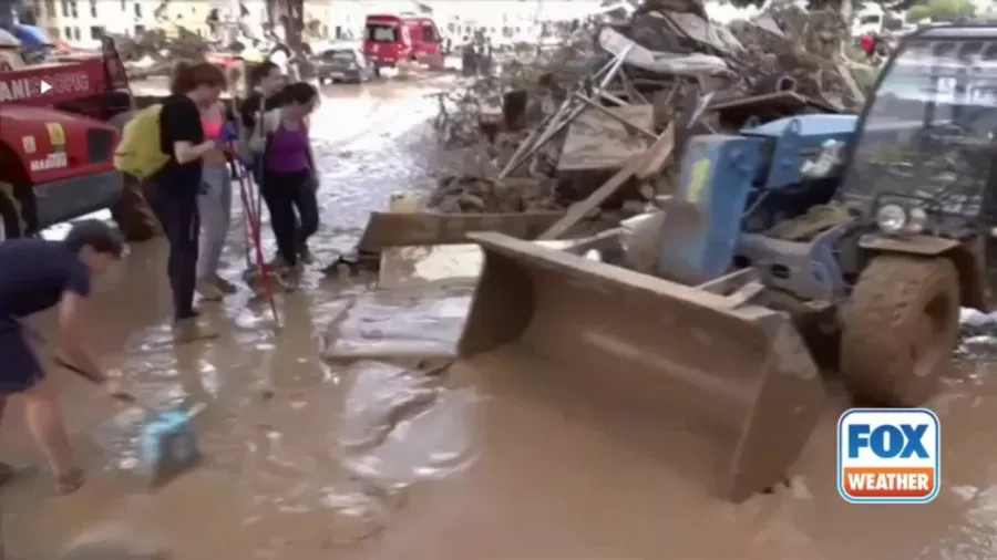 Hundreds sweep mud from flooded streets in Valencia region