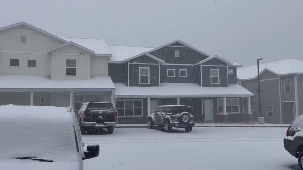 Lake effect snow blankets homes and cars in Oswego, New York.