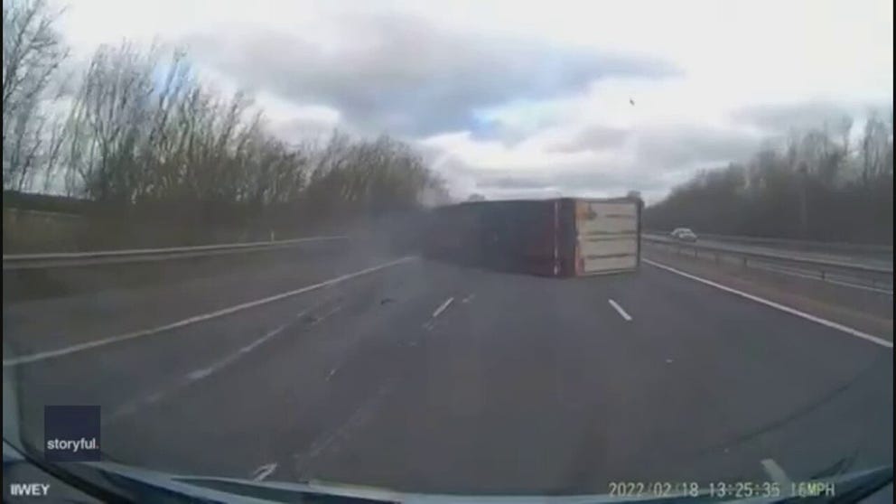 Watch how powerful winds from Storm Eunice were Friday in England. They knocked over a truck and a very lucky driver following caught it on dash cam safely.