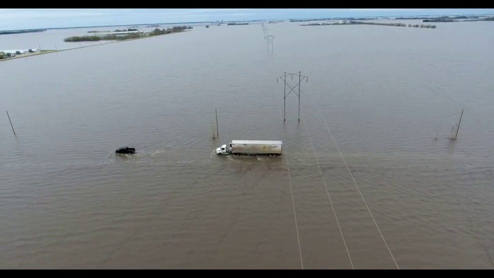 A truck picking up fresh eggs tenuously departs the Siemens Farms where the roadway is now part of a lake under a foot of water.