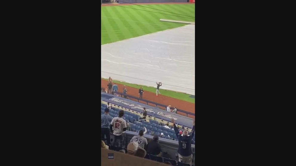 Cleveland Guardians player Myles Straw tossed a football with Yankees fans during a rain delay at Yankee Stadium of the decisive ALDS game Monday.