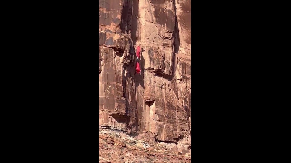 Video by hikers near Moab, Utah, shows a BASE jumper’s parachute catching a gust of wind, before he slams into a 400-foot cliff. The jumper was later rescued. (Credit: Baron Edwards)