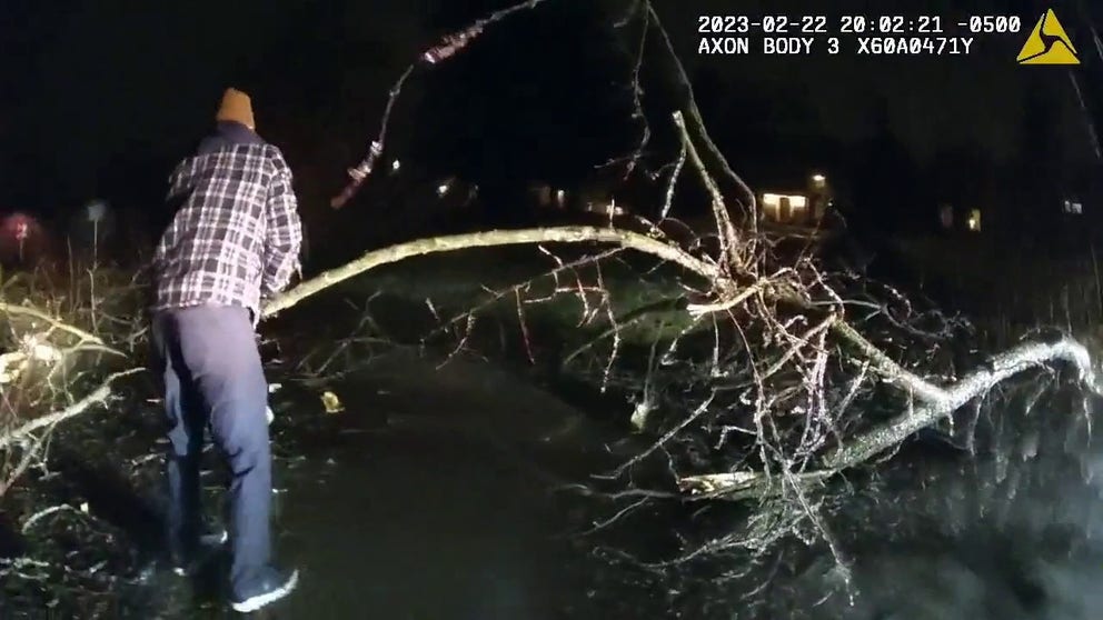 Police bodycam footage shows the Michigan Wolverines coach helping remove a large tree that had fallen and blocked the road. (Courtesy: Ann Arbor Police)