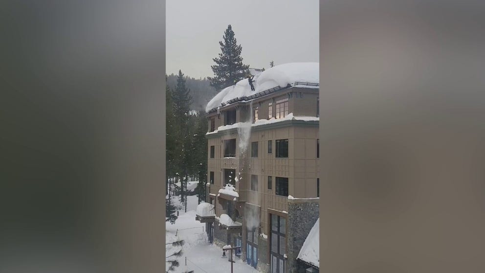 Workers at the Northstar California Resort in Truckee, California try and clear massive piles of snow off the roof of a building. 