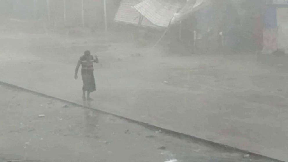 Residents in Sittwe, Myanmar, are seen braving the elements as wind-driven rain whips through a town as powerful Cyclone Mocha tears through the region on Sunday, May 14, 2023.
