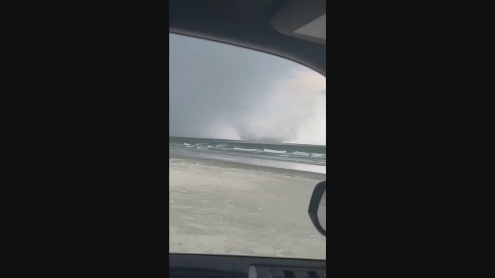 A couple on New Smyrna Beach, Florida sheltered in their car as a tornado spun up on the beach then passed over them. They continued the video as the twister moved offshore where meteorologists call it a waterspout.