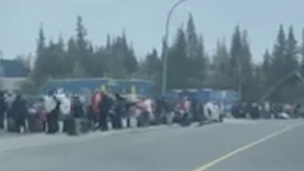 The video shows a line of people with suitcases waiting near Sir John Franklin High School on 49 Street in Yellowknife, Canada, where the local government instructed residents evacuating by air to go on Thursday. (Courtesy: @vincemeslage via Storyful)