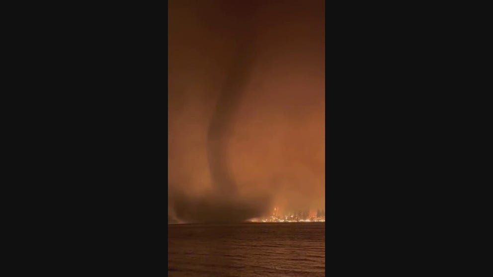 Dramatic video recorded in British Columbia, Canada, shows what appears to be a tornado or waterspout spinning along a lake as a raging wildfire scorched the nearby landscape.