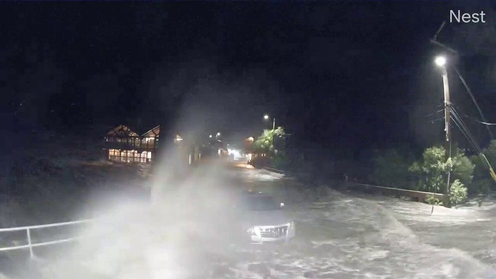 Impressive waves riding on the storm surge crash over a car parked on a coastal road in Cedar Key, Florida. 