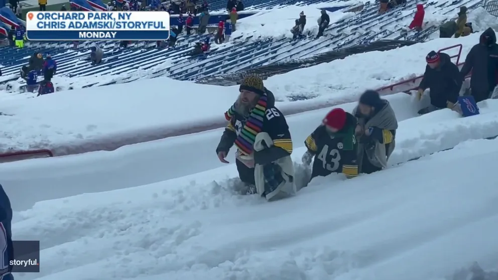 A committed Steelers fan works as a human snowplow to clear a row of seats.