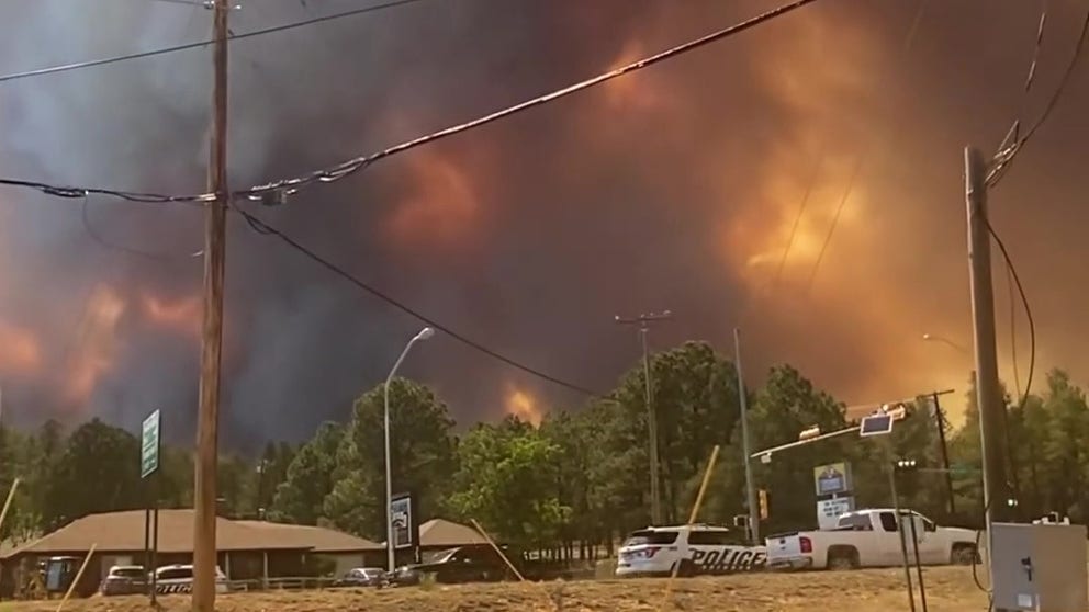 Residents of an entire New Mexico town were told to flee Monday evening after a wildfire exploded in size and spread, burning some structures and threatening more.