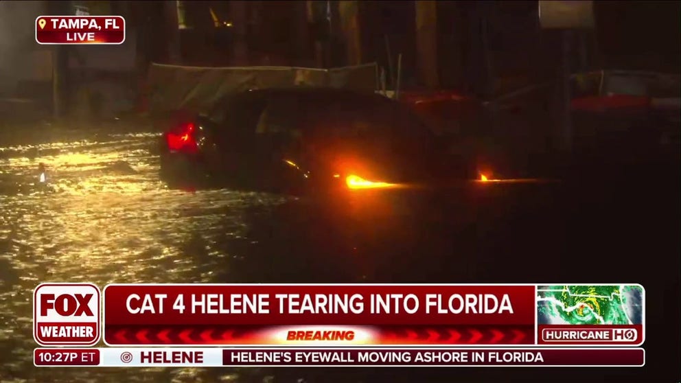 People seen in Tampa trying to push car through Hurricane Helene floodwater.