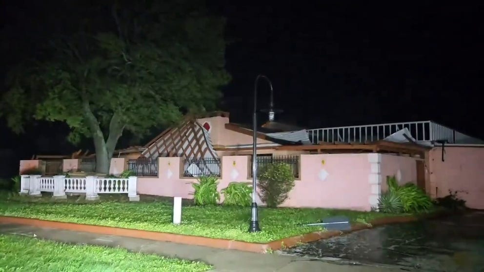 The roof of a home and the entry to a neighborhood in Sarasota, Florida, were damaged during Hurricane Milton's approach on Florida. 