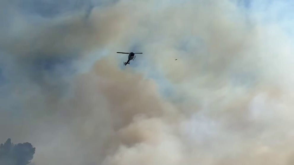 San Diego Fire Department air support works to drop water on the fire, which started Thursday. 