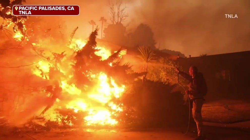 A video shared on Tuesday shows a man using a garden hose to extinguish a home engulfed in flames, before then becoming swallowed up in the flames himself. (Video courtesy: TNLA)