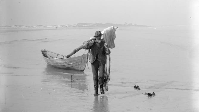Annisquam dory fisherman Addison Butler, carrying sail, mast and dip net. Coffin's Beach. 1895. photo: Martha H. Harvey.
