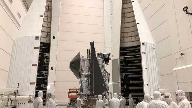 A picture showing the Lucy spacecraft and two rocket fairings in a clean room.