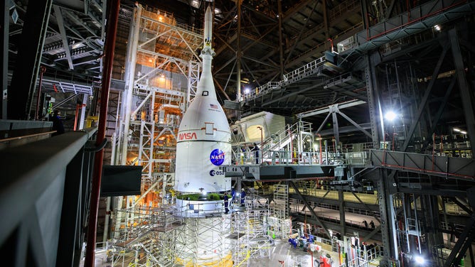 The Orion spacecraft for NASA’s Artemis I mission, fully assembled with its launch abort system, is lifted above the Space Launch System (SLS) rocket in High Bay 3 of the Vehicle Assembly Building at Kennedy Space Center in Florida on Oct. 20, 2021. The stacking of Orion on top of the SLS completes assembly for the Artemis I flight test. Teams will begin conducting a series of verification tests ahead of rolling out to Launch Complex 39B for the Wet Dress Rehearsal. Artemis I will be an uncrewed test flight of the Orion spacecraft and Space Launch System rocket as an integrated system ahead of crewed flights to the Moon.