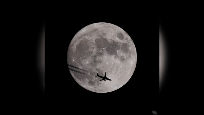 A plane flying in front of the full moon