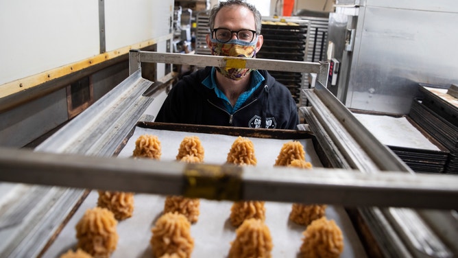 A baker looks at cookies on a tray.