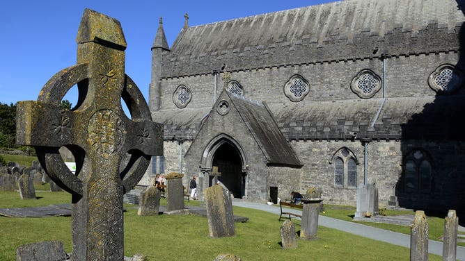 A traditional Celtic cross stands in the cemetery beside St. Canice's Cathedral in Kilkenny, Ireland.