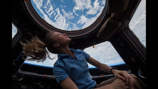 An astronaut floating in the cupola at the ISS looking at Earth.