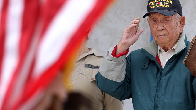 Louis Moore, a 98-year-old Chinese-American WWII veteran, salutes the presentation of the flags.