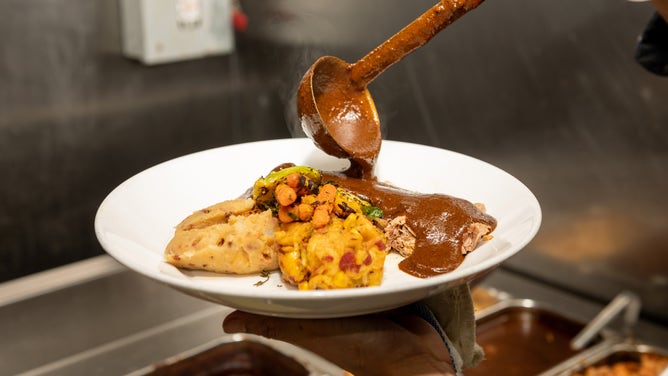 A chef pours mole sauce over turkey pieces as part of Rosa Mexicano's Thanksgiving dinner near Lincoln Center on November 26, 2020 in New York City.