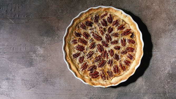 Fresh home baking classic American pecan caramel pie in white ceramic baking dish.