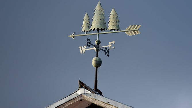 A Christmas tree weather vane on the roof of a barn.