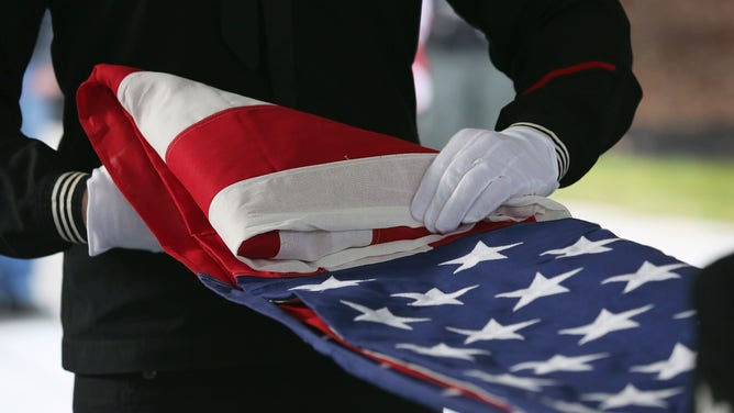 A U.S. Navy honor guard folds an American flag after removing it from the casket of a Vietnam War veteran.