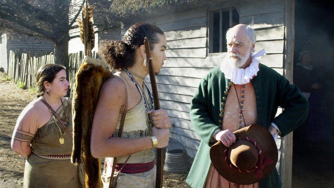 John Kemp (R) portrays pilgrim Steven Hopkins meeting with the colonists Wampanoag Indian interpreter Hobbamock, played by Jonathan Perry (C), as another Wampanoag, played by Melanie Roderick (L), looks on at Plimoth Patuxet Museum's recreation of the first Thanksgiving dinner in Plymouth, Massachusetts.