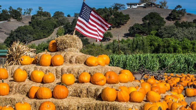 An American flag sits atop a mountain of pumpkins and straw bales in Solvang, California.