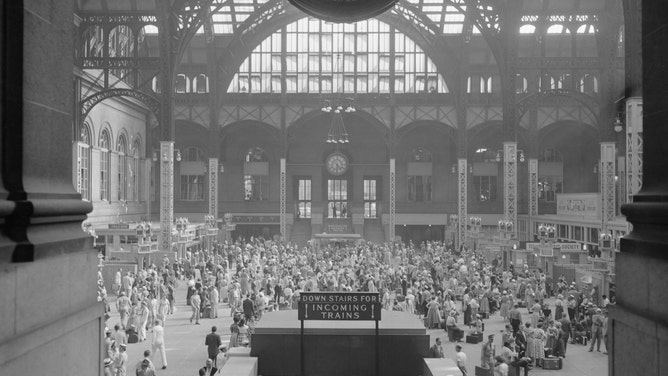 Travelers make their way between railway, bus, and airplane terminals at Penn Station in 1954 New York City.