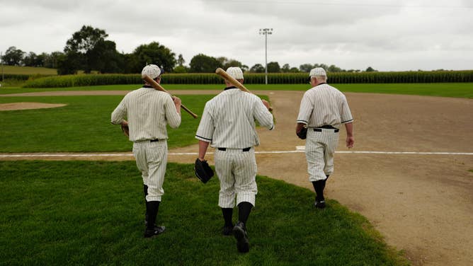 A small group of movie re-enactors gather in their 1919 Chicago White Sox uniforms to perform scenes from the movie "Field of Dreams" and play with the many children who visit the site each year.