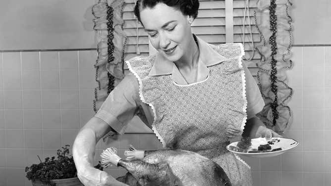 Woman in the 1950s placing start-shaped slices of canned cranberry sauce around a turkey.