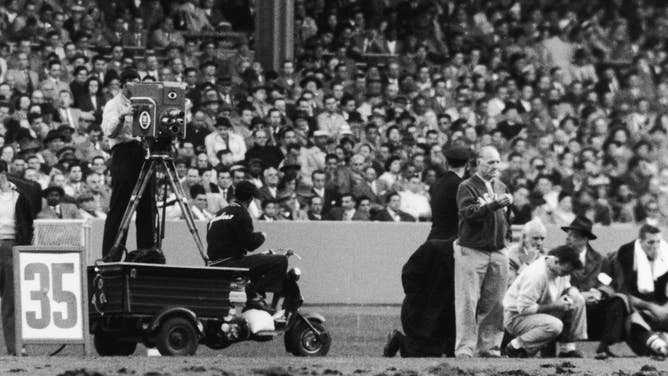 View of the television crew, consisting of a driver and a camera man behind a cart-mounted camera, on the sidelines during CBS Television's first televised American football game a Yankee Stadium between the New York Giants and the Philadelphia Eagles, New York, New York, October 28, 1956. The Gianst won the game 20-3. (Photo by Robert Riger/Getty Images)