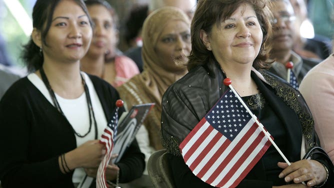 Holding U.S. flags, immigrants are sworn in as U.S. citizens during their citizenship ceremony.