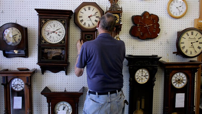 Howard Brown hangs a clock he repaired at Brown's Old Time Clock Shop in Florida.