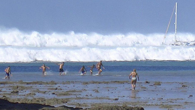 Foreign tourists far out on the sand after the water receded react as the first of six tsunamis starts to roll toward Hat Rai Lay Beach, near Krabi in southern Thailand, Dec. 26, 2004.